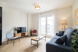 Una sala de estar moderna con un sofá, una mesa de centro, un televisor y una planta.