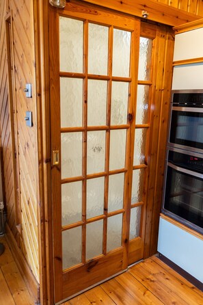 A wooden door with a frosted glass panel, a stainless steel oven, and a light switch on the wall. - Flat, Arthur Seat view, walking distance to Castle (Edinburgh)