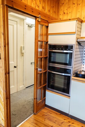 A kitchen with wooden paneling, a white door, and a stainless steel oven. - Flat, Arthur Seat view, walking distance to Castle (Edinburgh)