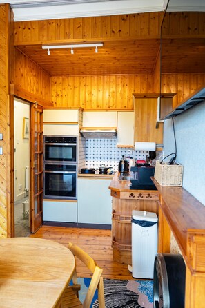 A compact kitchen with wooden walls and a dining area. - Flat, Arthur Seat view, walking distance to Castle (Edinburgh)