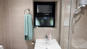A bathroom with a sink, a towel rack with a towel, a mirror, and a shower area. - Spacious 2-BR Annexe near Abington Park - 10% off (West Northamptonshire)