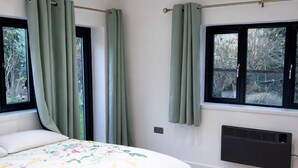 A bedroom with a bed, green curtains, a window, and a radiator. - Spacious 2-BR Annexe near Abington Park - 10% off (West Northamptonshire)