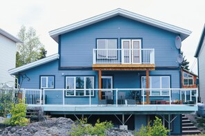 A two-story house with a balcony, satellite dishes, and a wooden deck. - Charming Retreat with Stunning Views in Yellowknife's Prestigious Neighborhood (Yellowknife)