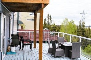 An outdoor deck with a wooden pergola, a table and chairs, and a view of a forested area. - Charming Retreat with Stunning Views in Yellowknife's Prestigious Neighborhood (Yellowknife)