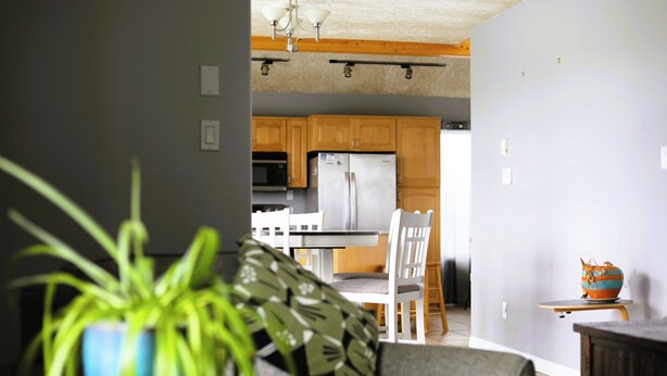 A modern kitchen with wooden cabinets, a refrigerator, and a dining area with a table and chairs.