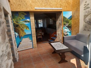 Ein Zimmer mit Blick auf einen tropischen Strand, einem Essbereich mit Tisch und Stühlen sowie einer Couch.