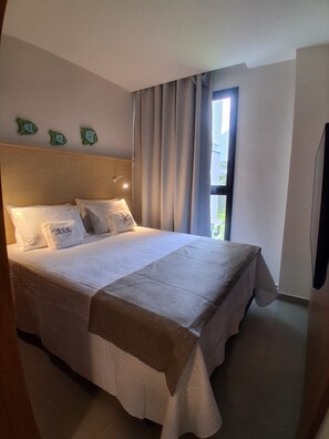 Ein Hotelzimmer mit einem Bett, Vorhängen, einem Fenster und einer Wandleuchte.