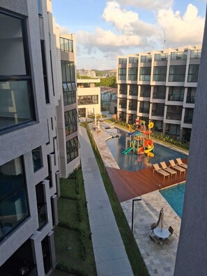 A modern building with a swimming pool, outdoor seating, and a children's play area. - F.206 | Your Refuge with comfort and good taste (Tamandaré)