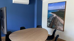 A conference room with a round table, black chairs, a mounted TV, and a large scenic wall art. - F.206 | Your Refuge with comfort and good taste (Tamandaré)