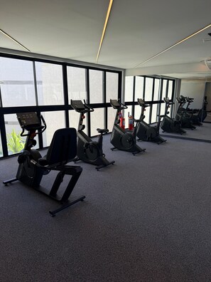 A gym with multiple exercise machines, large windows, and a carpeted floor. - F.206 | Your Refuge with comfort and good taste (Tamandaré)