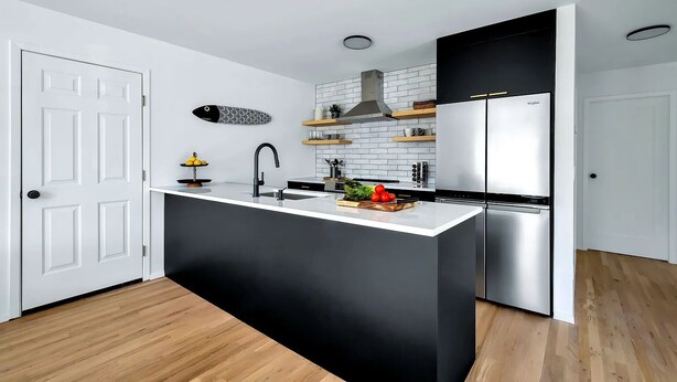 A modern kitchen with a black and white color scheme, a central island, and built-in appliances.