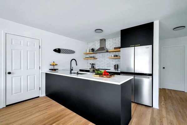 A modern kitchen with a black and white color scheme, a central island, and built-in appliances.