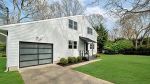 A two-story house with a garage, a front porch, and a well-maintained lawn.