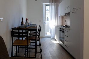 A compact kitchen with a dining area, a stove, and a view through a door. - Apartment 'La Casa Di Gio Mar 2' with Balcony, Wi-Fi and Air Conditioning (Monopoli)