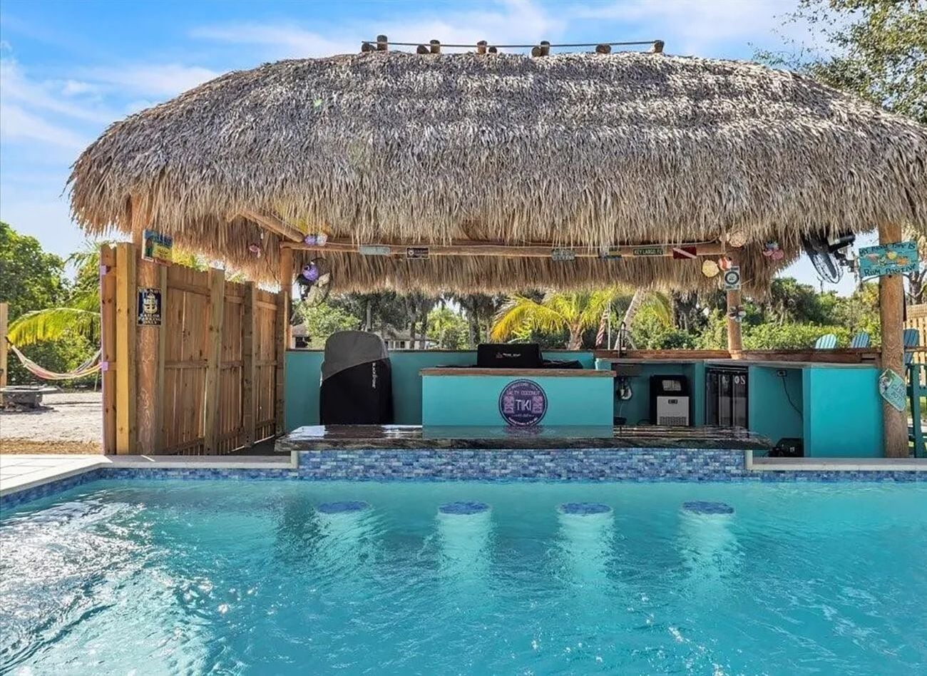A thatched tiki hut with a swim-up bar overlooks the swimming pool.