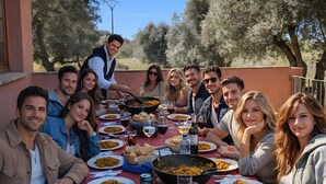 A group of people dining outdoors at a table with food and drinks.