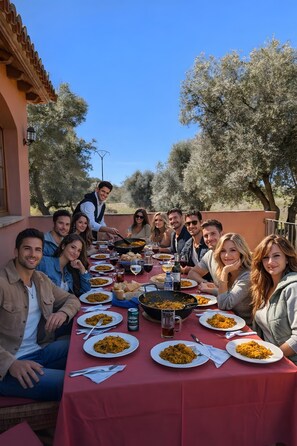 Un grup de persones dinuant a l'aire lliure a una taula plena d'aliments i begudes.