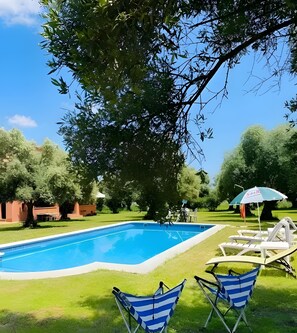 A swimming pool with lounge chairs and umbrellas, surrounded by trees and a grassy area. - Private Country House with Gredos Views (Calzada de Oropesa)