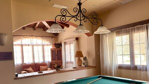 A pool table with balls, a sofa, a lamp, and a decorative horse head.