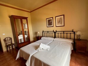 A neatly made bed with a patterned bedspread, a wooden headboard, two bedside lamps, a nightstand, and a chair.