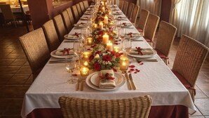 A long dining table set with candles, flowers, and tableware in a formal dining setting.