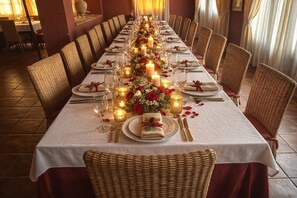 A long dining table set with candles, flowers, and tableware in a formal dining setting.