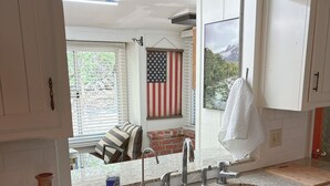 Een keuken met twee spoelbakken, een raam en uitzicht op een terras met een Amerikaanse vlag.