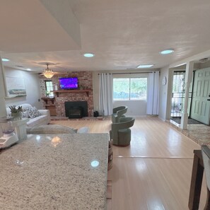 A spacious living room with a fireplace, a television, and a large window. - The Bridge at Springville PRIVATE RIVER ACCESS Sierra Foothills Near Sequoias (Springville)
