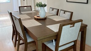 Ein Essbereich mit Holztisch, Stühlen, Deckenventilator und gerahmten Kunstwerken an den Wänden.