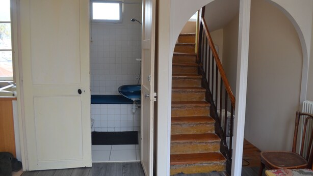 A staircase leading to a second floor, a bathroom with a blue sink, and a white door.