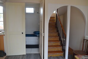 A staircase leading to a second floor, a bathroom with a blue sink, and a white door.