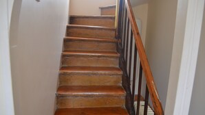 A wooden staircase with a black handrail leading to an upper floor.
