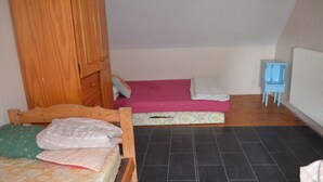 A bedroom with a wooden bed, a pink mattress, a small blue nightstand, and a radiator.