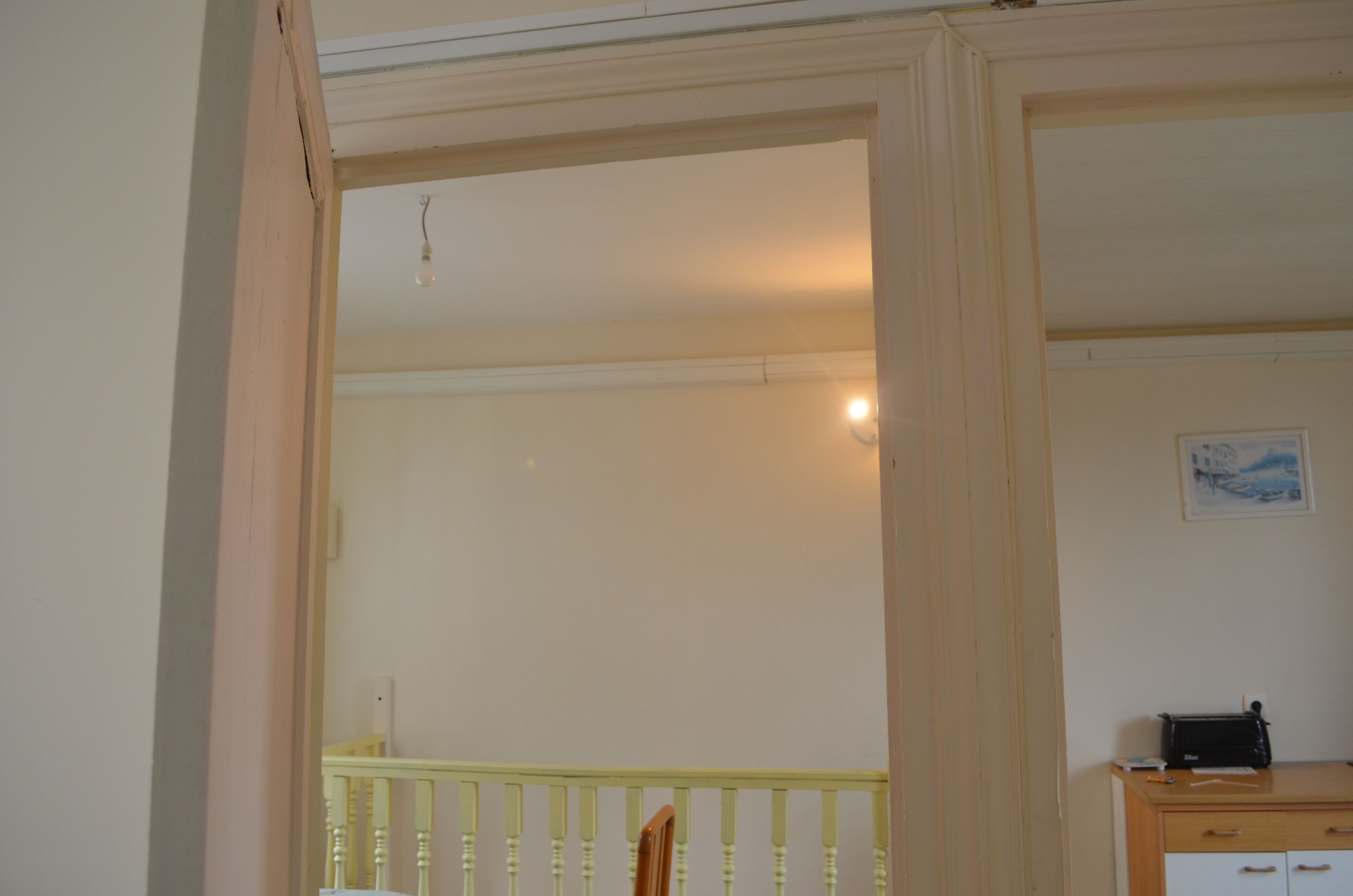 Ein Zimmer mit einem Holztisch, einem Stuhl, einem kleinen Tisch und einem gerahmten Bild an der Wand.