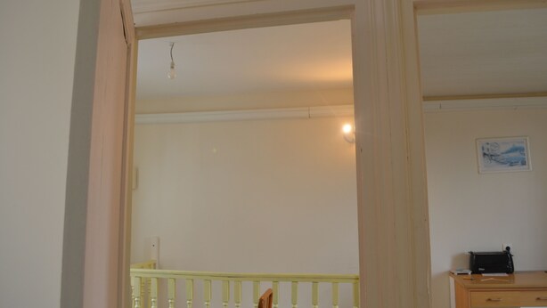 A room with a wooden desk, a chair, a small table, and a framed picture on the wall.