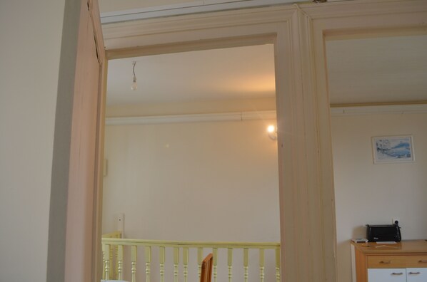 A room with a wooden desk, a chair, a small table, and a framed picture on the wall.
