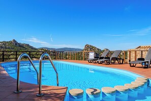 Ein Swimmingpool mit einer Metallleiter, Liegestühlen und einer Steinmauer.