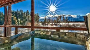 Un jacuzzi con vistas despejadas a un paisaje nevado y un sol brillante.