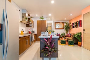 A modern kitchen with a coffee station, wooden cabinets, and a central island with a plant. - Roma Norte Grand Stay 3BR / AC (Ciudad de México)