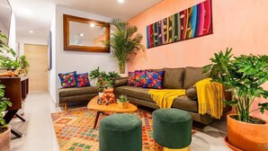 Ein modernes Wohnzimmer mit einer Couch, Poufs, einem Couchtisch und Topfpflanzen.