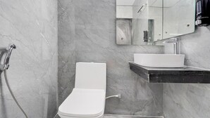 Un baño con inodoro, lavamanos, espejo y ducha.