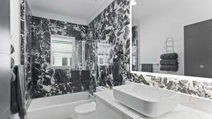 A modern bathroom with a marble backsplash, a large mirror, a bathtub, a toilet, and a sink. - Hyde Park 1/1 private residence 12 (Tampa)