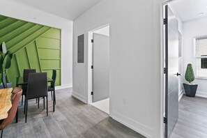 Een modern interieur met een eethoek, een groene accentmuur en een potplant.
