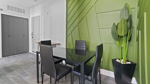 A modern dining area with a glass table, black chairs, and a green accent wall. - Hyde Park 1/1 private residence 12 (Tampa)