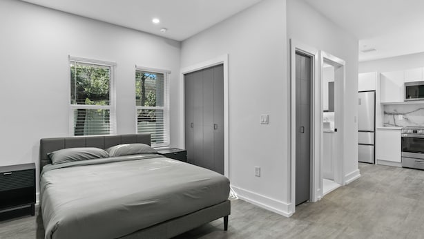 Camera moderna con un letto grande, una cabina armadio e un angolo cottura.