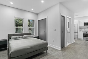 Ein modernes Schlafzimmer mit einem großen Bett, einem begehbaren Kleiderschrank und einer Küchenzeile.