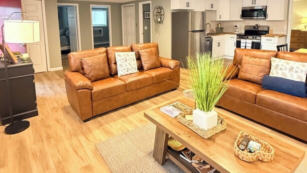 A modern living room with a brown leather sofa, a wooden coffee table, and a kitchen in the background.