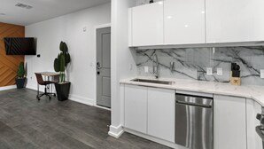 A modern kitchen with white cabinets, a marble backsplash, and a stainless steel dishwasher.