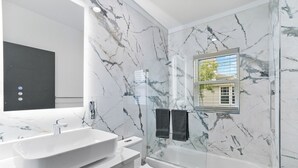 A modern bathroom with a large white sink, a toilet, and a glass-enclosed bathtub. - Hyde Park 1/1 private residence 6 (Tampa)