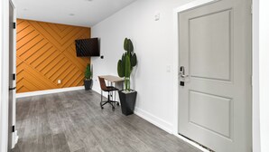 A hallway with a wooden wall, a door, a desk, a chair, and potted plants. - Hyde Park 1/1 private residence 6 (Tampa)